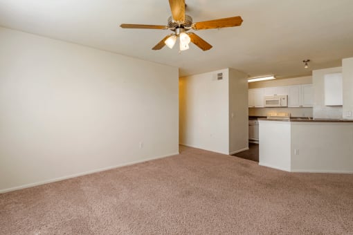 Living room with carpet flooring, multi speed ceiling fan, and kitchen breakfast bar