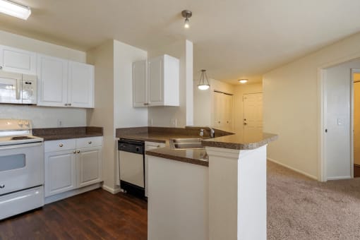 Kitchen with white appliances, hardwood style flooring, and white cabinets