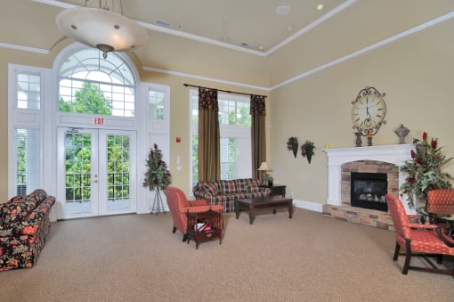 Resident clubhouse with seating throughout including multiple couches and chairs. A fireplace rests to the right of the room
