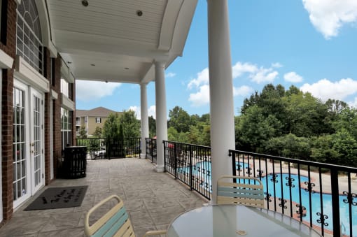 Clubhouse deck with a round table and seating. The deck overlooks the pool and has a end to end guard rail.