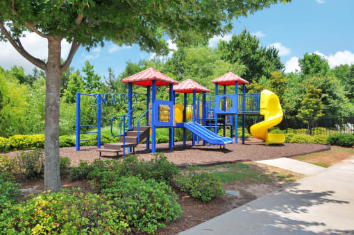 Playground with obstacles and a slide. The playground is made of mostly plastic and surrounded by a mulch bed.