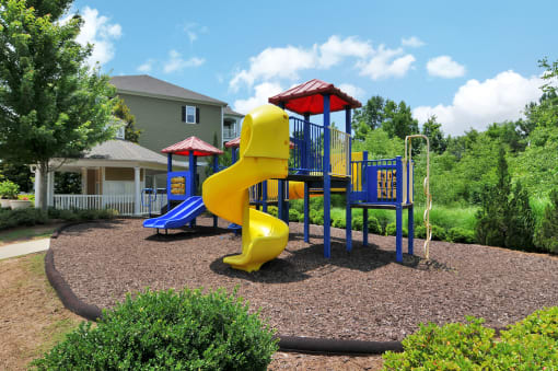 Children's playground with slides and other obstacles. The playground is surrounded by a mulch bed.