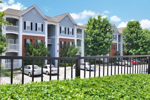 Building exterior comprised of brick and vinyl with windows throughout. resident parking lot can be seen in the foreground.