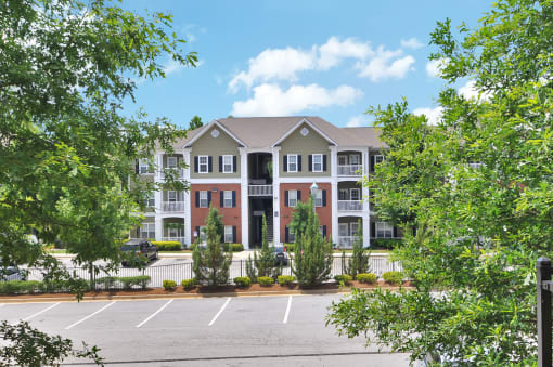 Building exterior comprised of brick and vinyl with windows throughout. resident parking lot can be seen in the foreground.