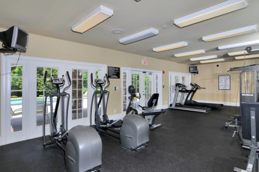 Resident fitness center with treadmills, ellipticals, and stationary bikes. Windows overlook the pool.