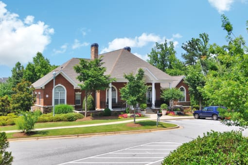 Community leasing office is comprised of red brick with windows along the front side of the building. Parking area in front.