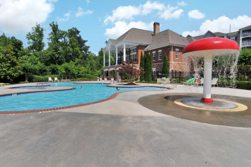 Community swimming pool with kid splash area on the right side. The resident clubhouse is in the background.