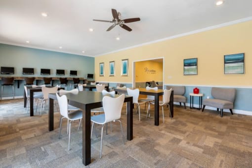 Clubhouse with Large Windows Black Tables with White Chairs Mounted TV and Ceiling Fans
