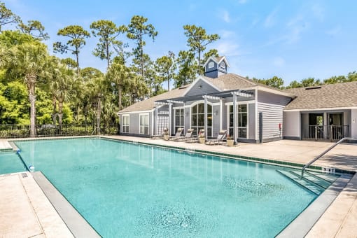 Rectangle swimming pool outside the clubhouse with several pool lounge chairs.