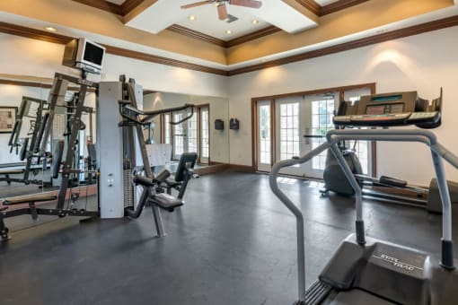 Fitness center equipped with strength training equipment, cardio equipment, multi speed ceiling fan, and large mirrors