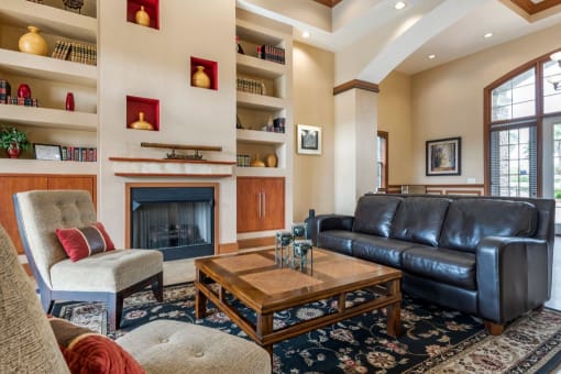 Clubhouse lounge with couches, chairs, coffee table, rug, fire place, and book shelves