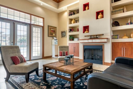 Clubhouse lounge with fire place, built-in book shelves, rug, couch, chairs, coffee table, and large windows for natural lighting