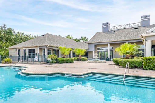 Swimming pool with a brick paver sundeck, palm trees, and lounge chairs.