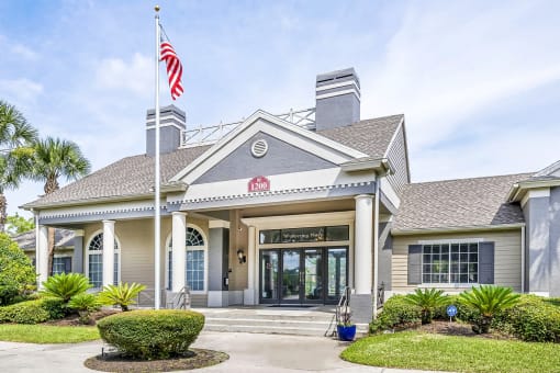 Exterior view of the leasing office with a sidewalk, four steps, and a flag pole with an American flag.