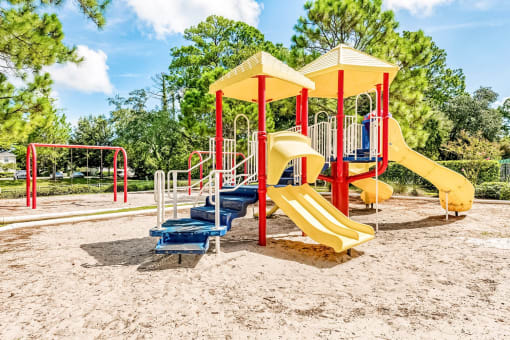 Large playground structure with several yellow slides and a red swing set.