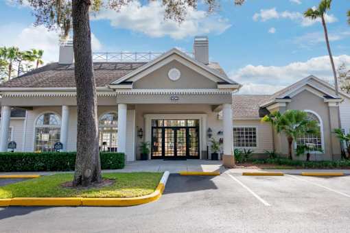 Parking Lot in Front of Clubhouse with Sidewalk Lined with Shrubs and Trees