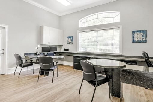 Leasing office with a long countertop in between two desks with computers, cabinets, and hardwood-style flooring.