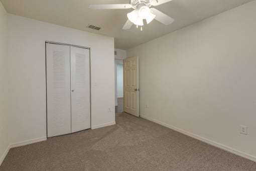 Carpeted Room with Folding Closet Door and Ceiling Fan