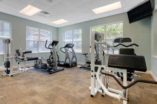 Fitness center equipped with strength training equipment, cardio equipment, and mounted tv