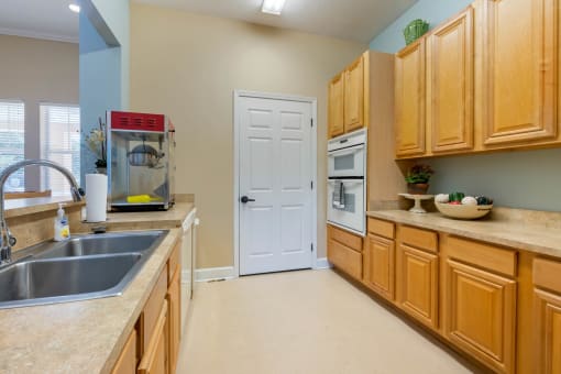 Clubhouse Kitchen with beige cabinets, white appliances, and breakfast bar and popcorn machine
