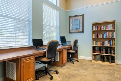 Business center with 2 desktop computers with a book shelf in the background
