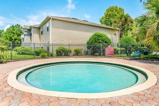 Round wading pool surrounded by brick pavers.