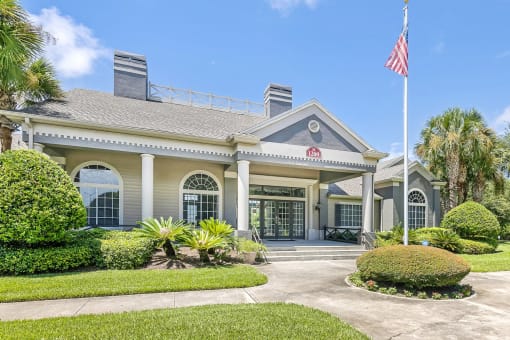 Exterior view of the leasing office with a sidewalk, four steps, and a flag pole with an American flag.