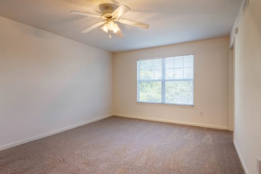 Carpeted Bedroom with white walls and one widow and ceiling fan