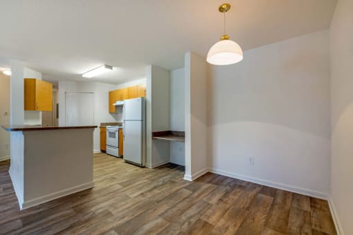Dining Room with wood floors, white walls, and built in desk with view of the kitchen in the back