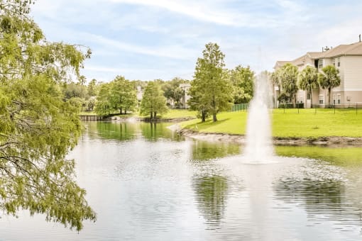 Large community lake with a water feature surrounded by grass and native landscape.