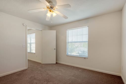 Carpeted Bedroom with white walls and one widow and ceiling fan