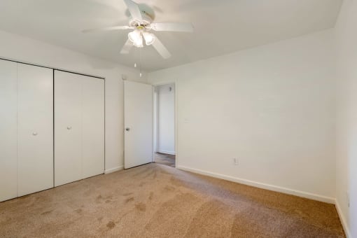 Carpeted Bedroom with white walls and one widow, double door closet, and ceiling fan