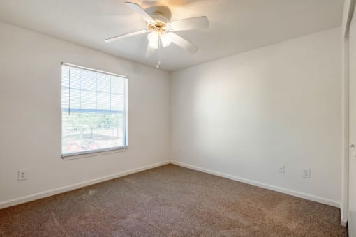 Carpeted Bedroom with white walls and one widow and ceiling fan