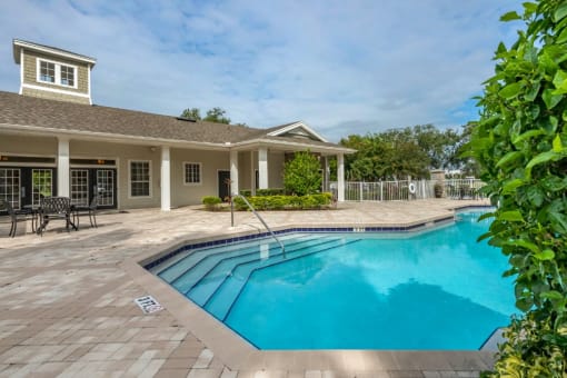 Swimming pool with lounge seating and clubhouse in the background
