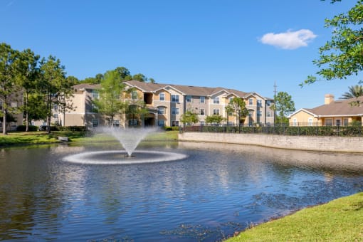 Lake view with fountain in the middle and exterior buildings in the back ground