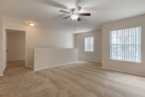 Spacious living room with carpet flooring, multi speed ceiling fan, and large windows for natural lighting