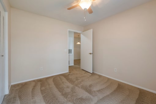 Spacious bedroom with carpet flooring and multi speed ceiling fan