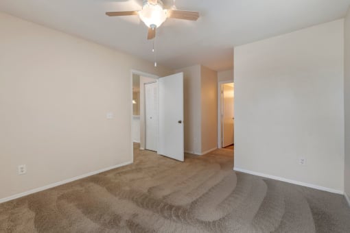Spacious bedroom with carpet flooring, multi speed ceiling fan, and in-suite bathroom