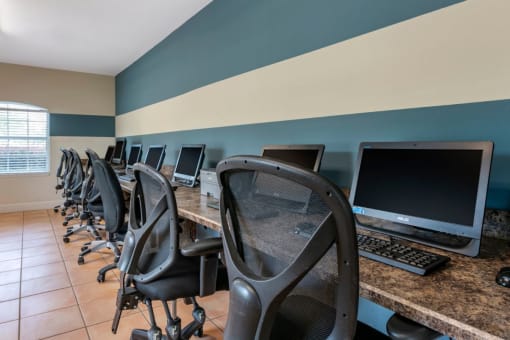 Resident business lounge with tile flooring, chairs, computers, and large window for natural lighting