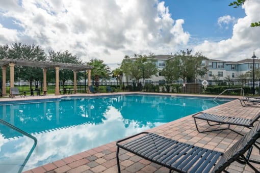 Swimming pool with sundeck, lounge seating, surrounded by native landscaping