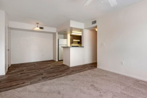 Spacious living room with carpet flooring, dining room with hardwood style flooring, and kitchen breakfast bar