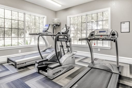 Fitness center with cardio machines, large windows and television
