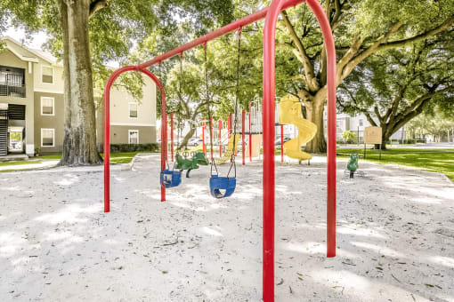Swing set with playground in the background and surrounded by native landscape
