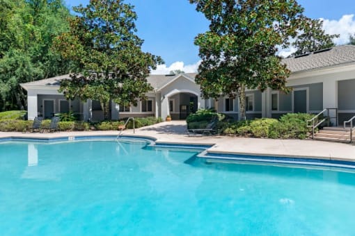 Swimming pool surrounded by native landscaping and clubhouse in the background