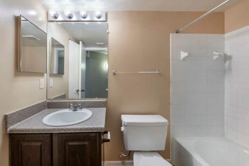 Bathroom with large mirror, vanity lighting, and tiled shower