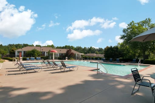 Swimming Pool and Sun Deck with Lounge Chairs with Trees and Building Exteriors in the Background
