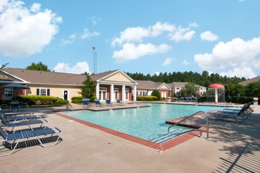 Swimming Pool and Sun Deck with Lounge Chairs with Trees and Building Exteriors in the Background