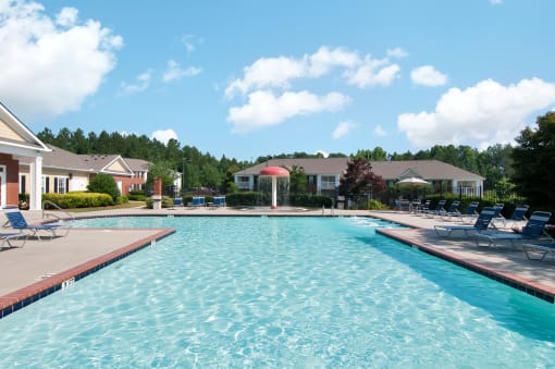 Swimming Pool and Sun Deck with Lounge Chairs with Trees and Building Exteriors in the Background