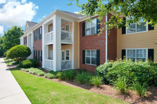 Exterior of apartment with a grass area and bushes by the building