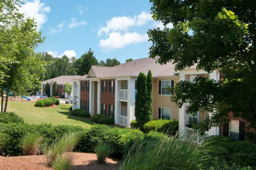Exterior of apartment with a grass area and bushes by the building